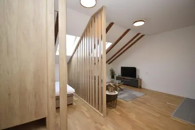 a room with a bed and a tv and wooden floors at Studio apartment Art Zone II in Podgorica