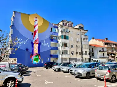 a parking lot with cars parked in front of a building at Homestay Mark - DOUBLE BED ROOM - shared bathroom in Budva