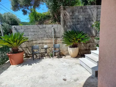 a patio with two chairs and a table and two plants at Apartmani Vujovic Markovici 2 in Budva