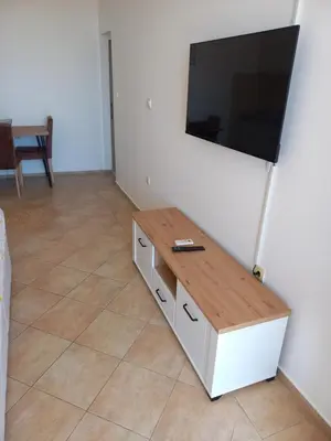 a living room with a table and a flat screen tv at Apartmani Vujovic Markovici 2 in Budva