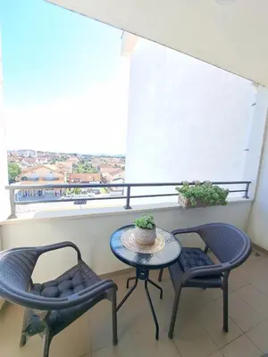 a balcony with a table and two chairs and a window at VUCETIC Apartment- Podgorica in Podgorica