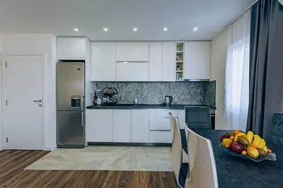 a kitchen with white cabinets and a table with a bowl of fruit at Bečići lux in Ivanovići