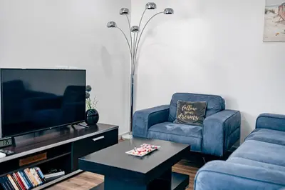 a living room with two blue chairs and a tv at Bečići lux in Ivanovići