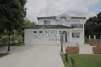 a white house with a large garage at Vila Mikeli in Podgorica