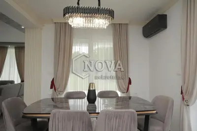 a dining room with a table and chairs and a chandelier at Vila Mikeli in Podgorica