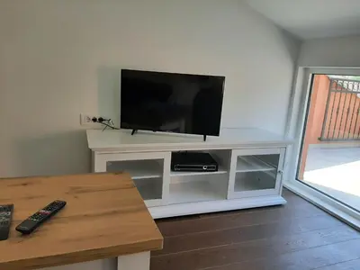 a flat screen tv sitting on a white entertainment center at Beautiful flat with sea view Aquamarine in Kotor