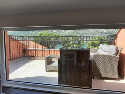 a balcony with wicker chairs and a glass window at Beautiful flat with sea view Aquamarine in Kotor