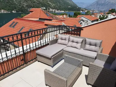 a balcony with a couch and chairs on a balcony at Beautiful flat with sea view Aquamarine in Kotor
