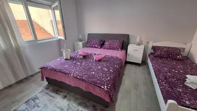 a bedroom with two beds with purple sheets and pillows at Apartman Jelena in Cetinje