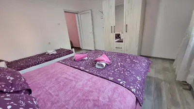 a room with two beds with purple sheets and pink pillows at Apartman Jelena in Cetinje