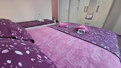 a bedroom with two beds with purple sheets and pink covers at Apartman Jelena in Cetinje