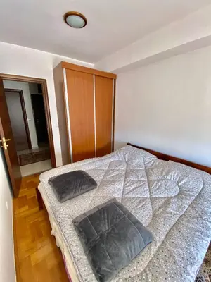 a bedroom with a bed and a wooden floor at Danilo's apartment in Podgorica