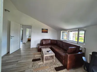 a living room with a brown leather couch and a table at Peaceful 2BR Apt with Ultra-Fast WiFi in Podgorica