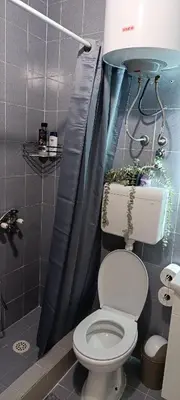 a bathroom with a toilet and a blue shower curtain at TEA7 apartment in Kotor