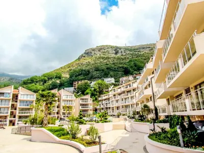 an apartment complex with a mountain in the background at Montetrest Apartments in Sveti Stefan