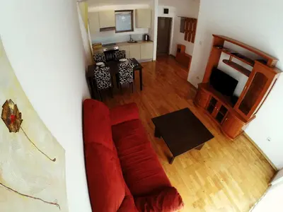 a living room with a red couch and a kitchen at Montetrest Apartments in Sveti Stefan