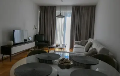 a living room with a couch and a table and chairs at Apartments Radovic in Podgorica