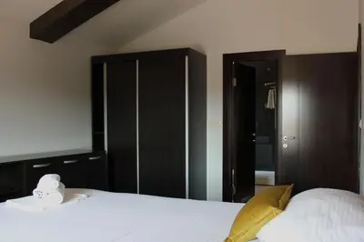 a bedroom with a large white bed with black cabinets at At Oliver’s in Budva