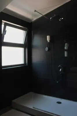 a bathroom with a shower and a window and a tub at At Oliver’s in Budva