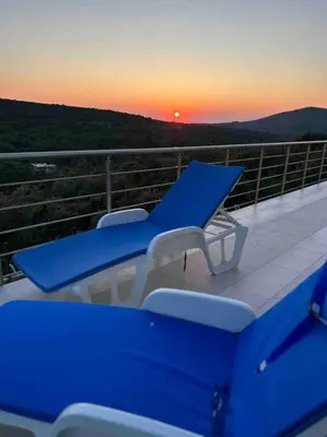 a blue table and chairs on a balcony with a sunset at Sunset house in Višnjevo