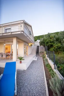 a house with a blue bench on the side of it at Sunset house in Višnjevo