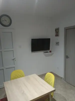 a table with yellow chairs and a television on a wall at apartman19 in Podgorica