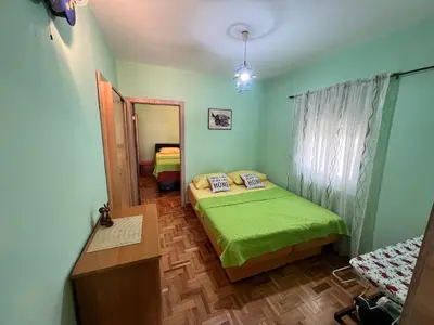 a bedroom with a green bed and a mirror at Central Park Apartment in Podgorica