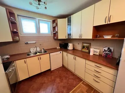 a kitchen with white cabinets and a wooden floor at Central Park Apartment in Podgorica