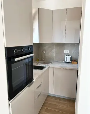 a kitchen with white cabinets and a black appliance at Apartments HAS in Kotor