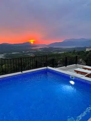 a swimming pool with a sunset in the background at Apartments HAS in Kotor