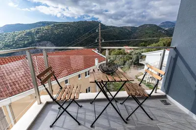 two chairs and a table on a balcony with mountains at Olive Tree Apartments in Becici