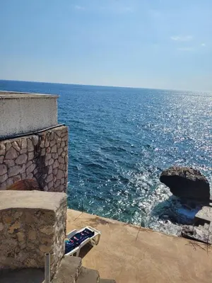a stone fireplace with the ocean in the background at SD LUX APARTMENTS in Dobra Voda