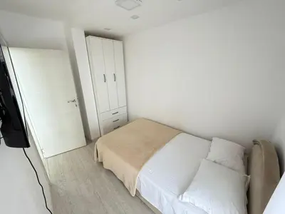 a white bedroom with a bed and a closet at Apartman Marija sa ličnim đakuzijem in Becici