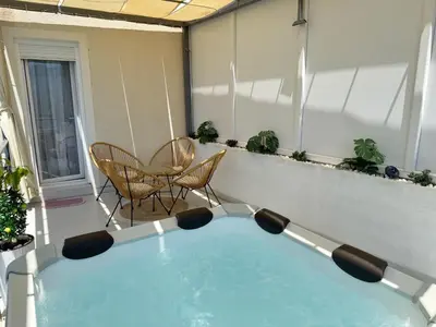 a hot tub on a balcony with a table and chairs at Apartman Marija sa ličnim đakuzijem in Becici