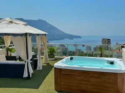 a hot tub on a balcony with a view of the ocean at Apartman Marija sa ličnim đakuzijem in Becici