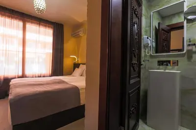a bedroom with a bed and a bathroom with a mirror at Hotel Premier in Budva