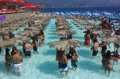 a group of people standing in the water under umbrellas at Apartment Butua. in Budva