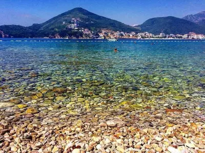 a rocky beach with a person swimming in the water at Apartment Butua. in Budva