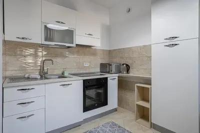 a kitchen with white cabinets and a sink at Apartment Anatolia of Becici in Becici