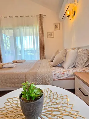 a bedroom with a bed and a table with a potted plant at Sunny Side Apartments in Rijeka Crnojevića