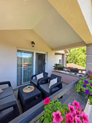 a patio with chairs and a table and flowers at Sunny Side Apartments in Rijeka Crnojevića