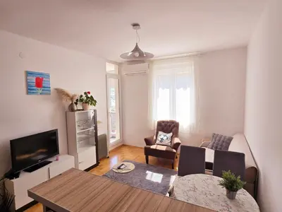 a living room with a table and chairs and a television at LaMar in Budva