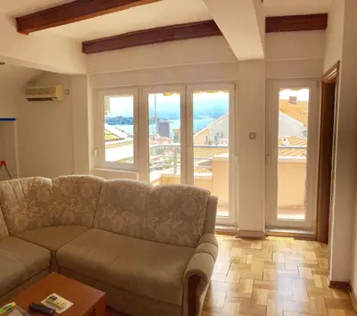 a living room with a couch and a large window at Apartman Bravo Budva in Budva