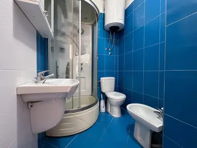 a blue tiled bathroom with a sink and a toilet at Apartman Bravo Budva in Budva