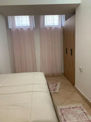 a bedroom with a large white bed and two windows at Podgorica city center apartment in Podgorica