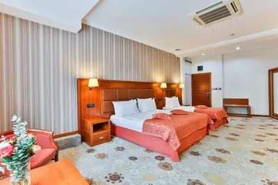 a hotel room with two beds and a chair at Kings Park Hotel in Podgorica