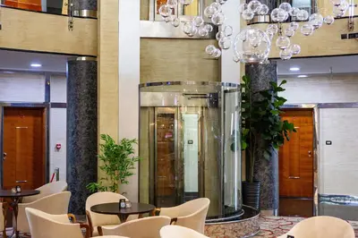 a lobby with tables and chairs and a large elevator at Kings Park Hotel in Podgorica