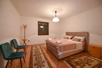 a bedroom with a bed and a green chair at Apartman Oskar in Podgorica