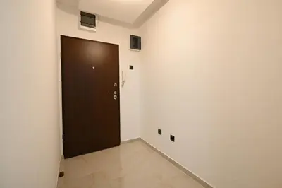 a hallway with a brown door in a white wall at Apartman Oskar in Podgorica