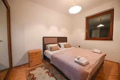 a bedroom with a bed and a dresser and a window at Apartman Oskar in Podgorica